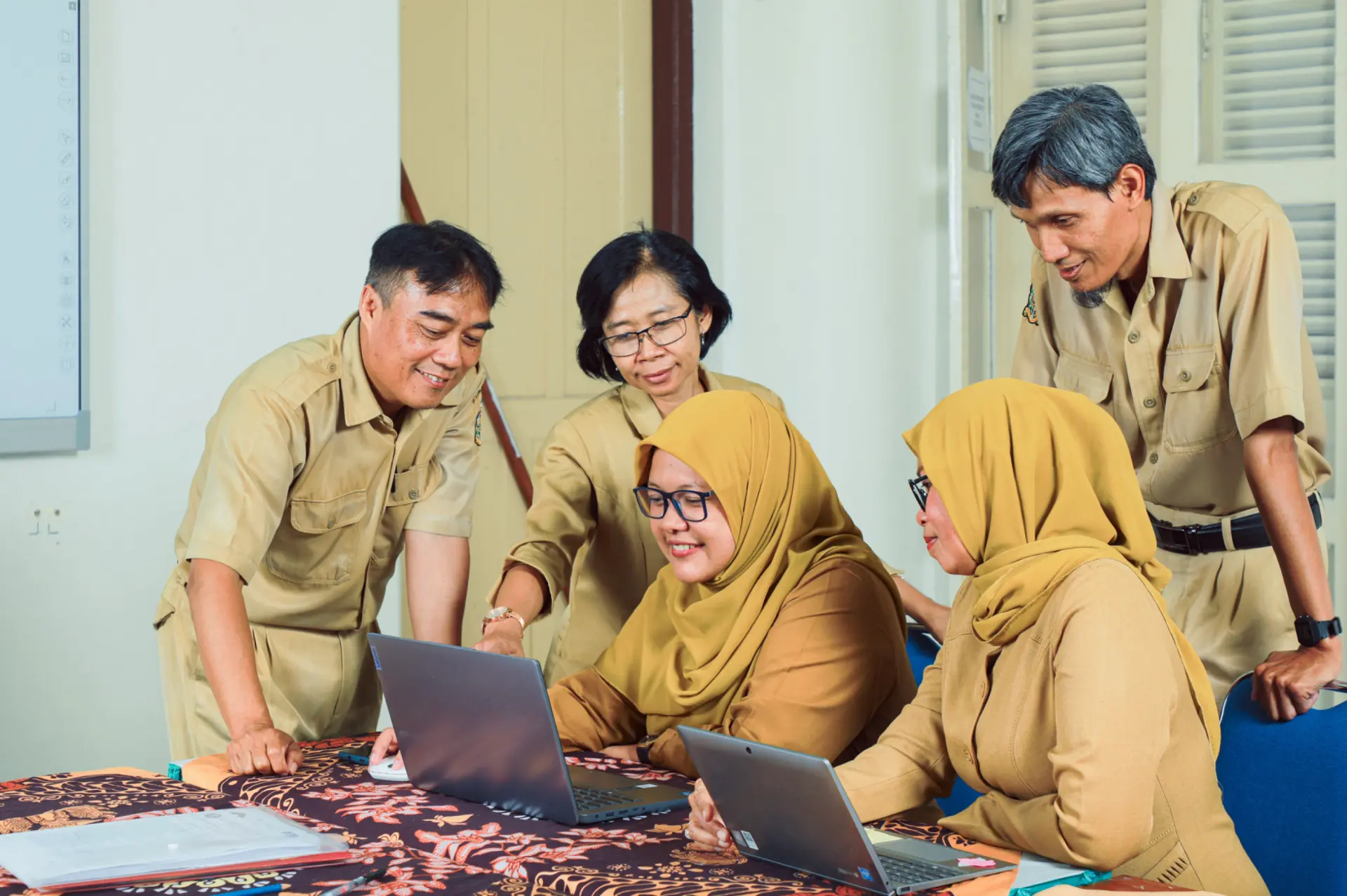 Tim guru berdiskusi menggunakan laptop